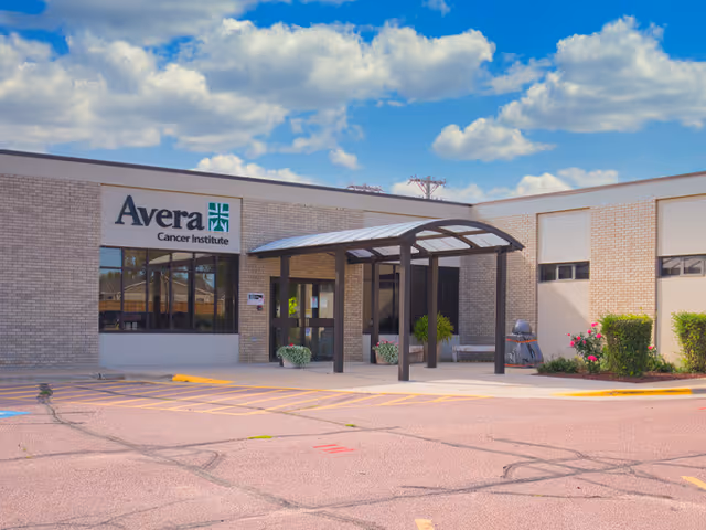 Exterior view of the Avera Cancer Institute building with a curved sheltered entrance and parking area.