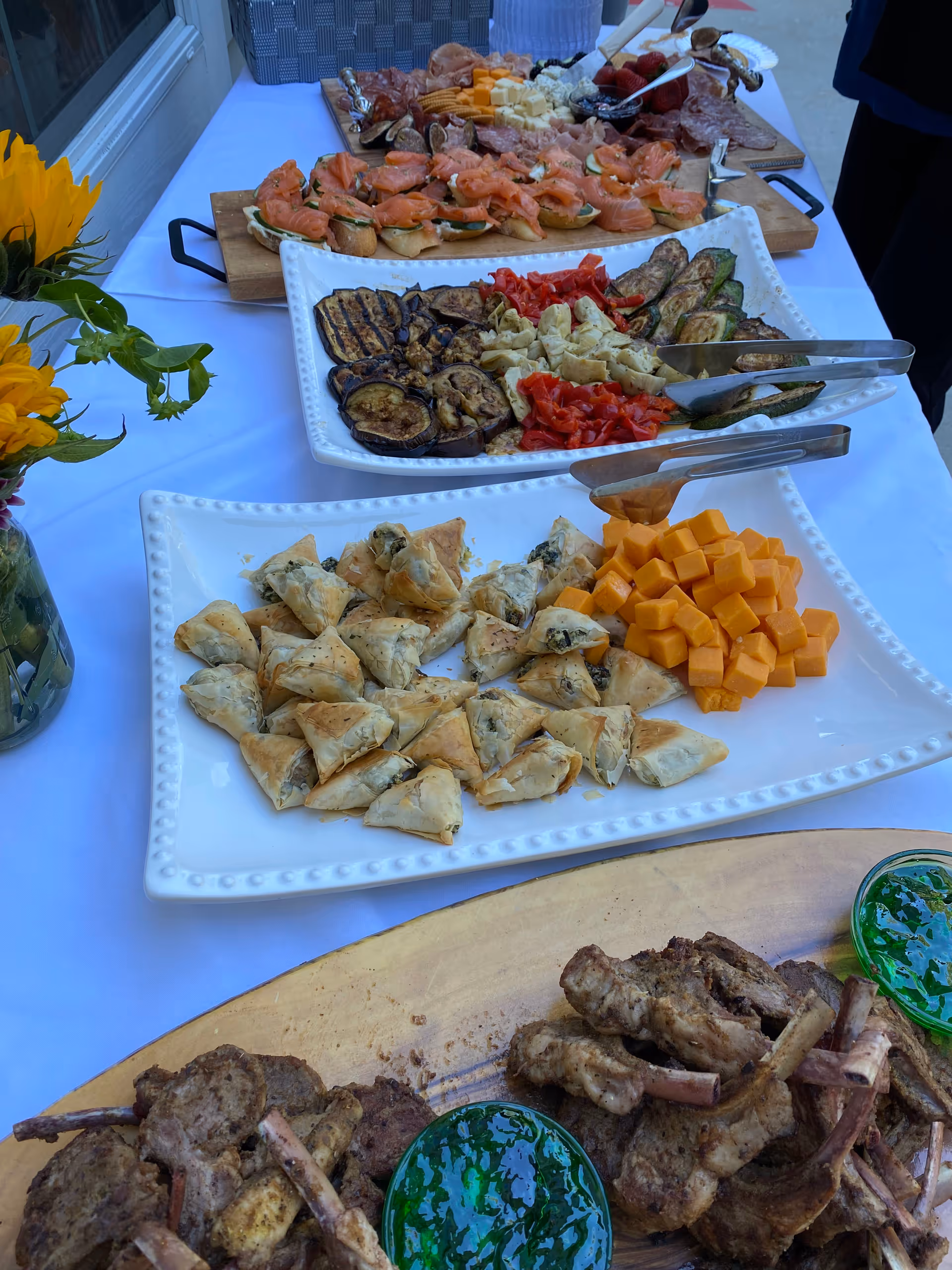Buffet table with cheese cubes, pastries, grilled vegetables, and assorted meats.