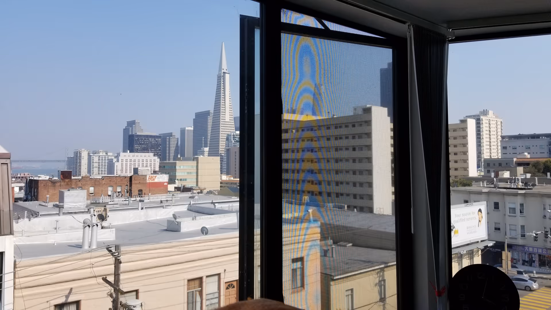 City skyline visible through a large interior window framed by blinds.