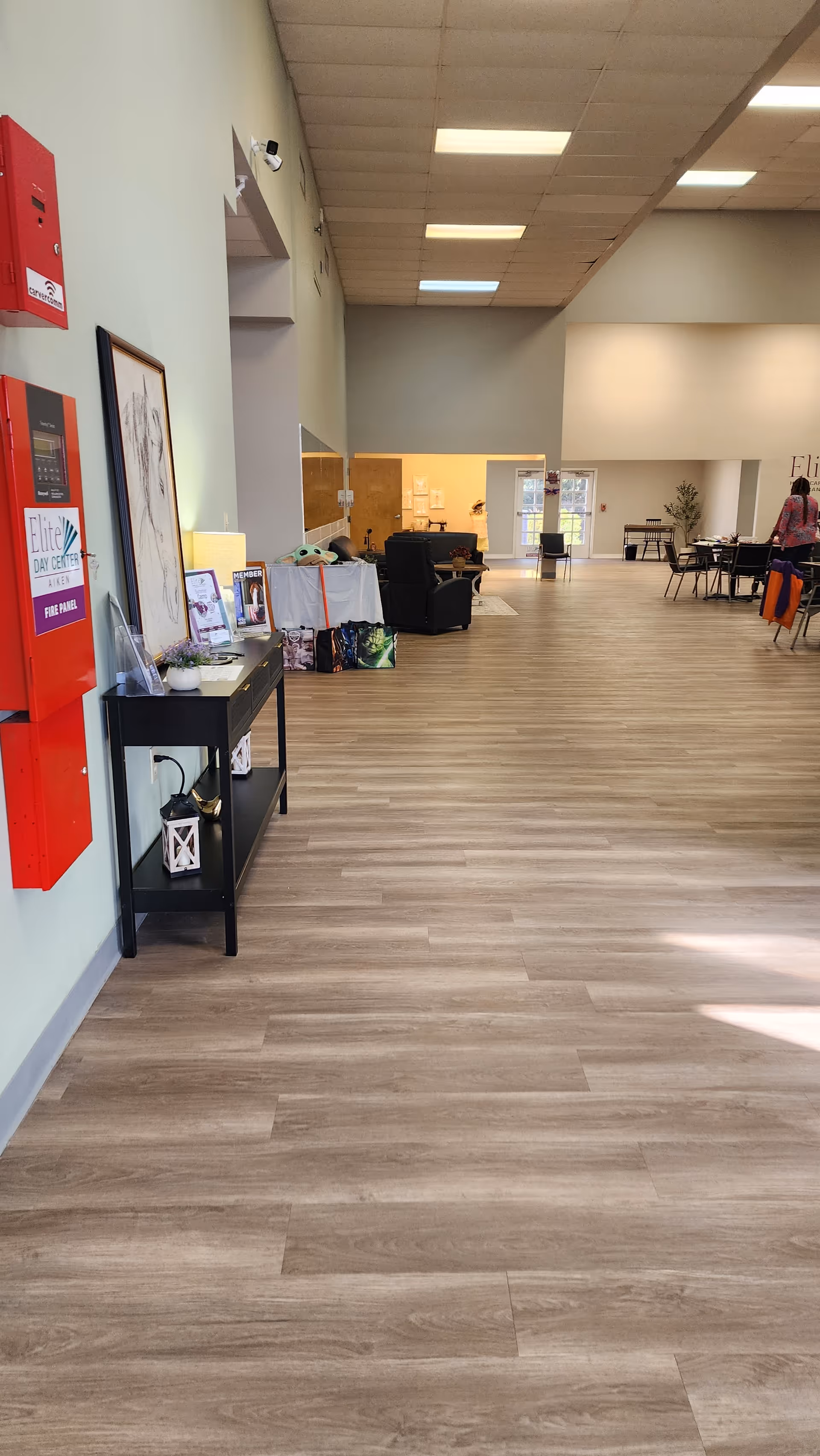A wide, well-lit hallway in a senior living facility with a reception desk and seating.