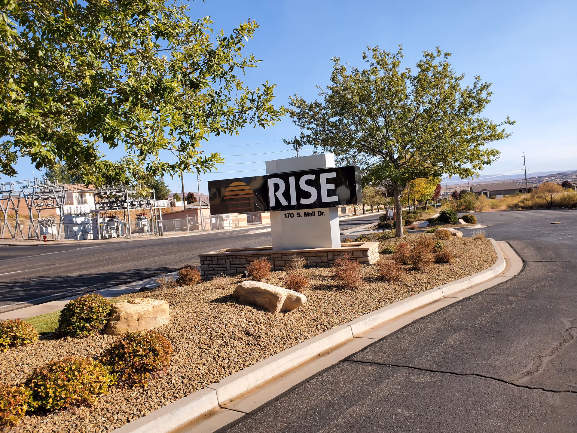 Exterior view of a Rise sign amid desert landscaping and a curved driveway.
