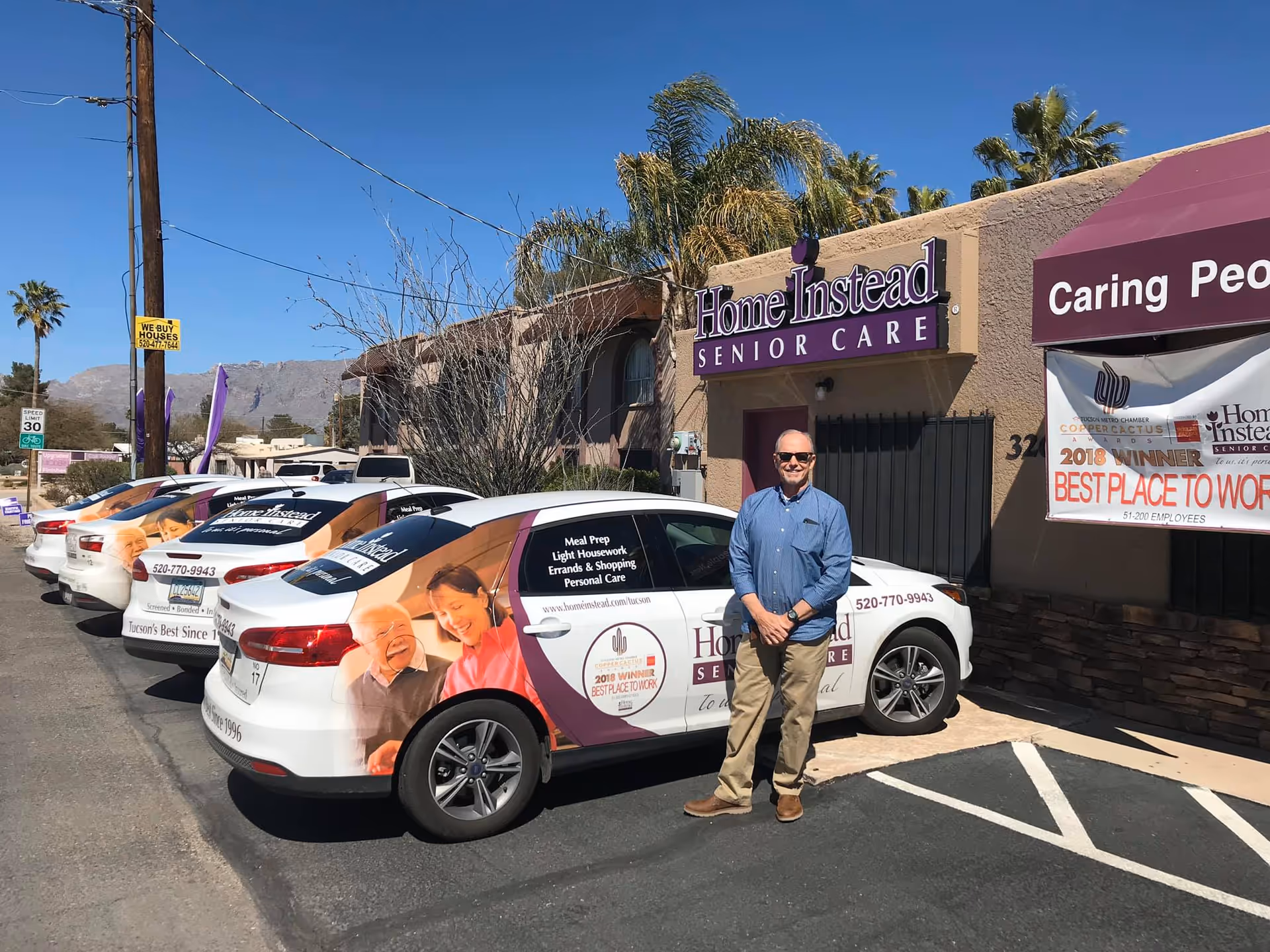 Man stands by branded Home Instead Senior Care cars outside the facility's front.