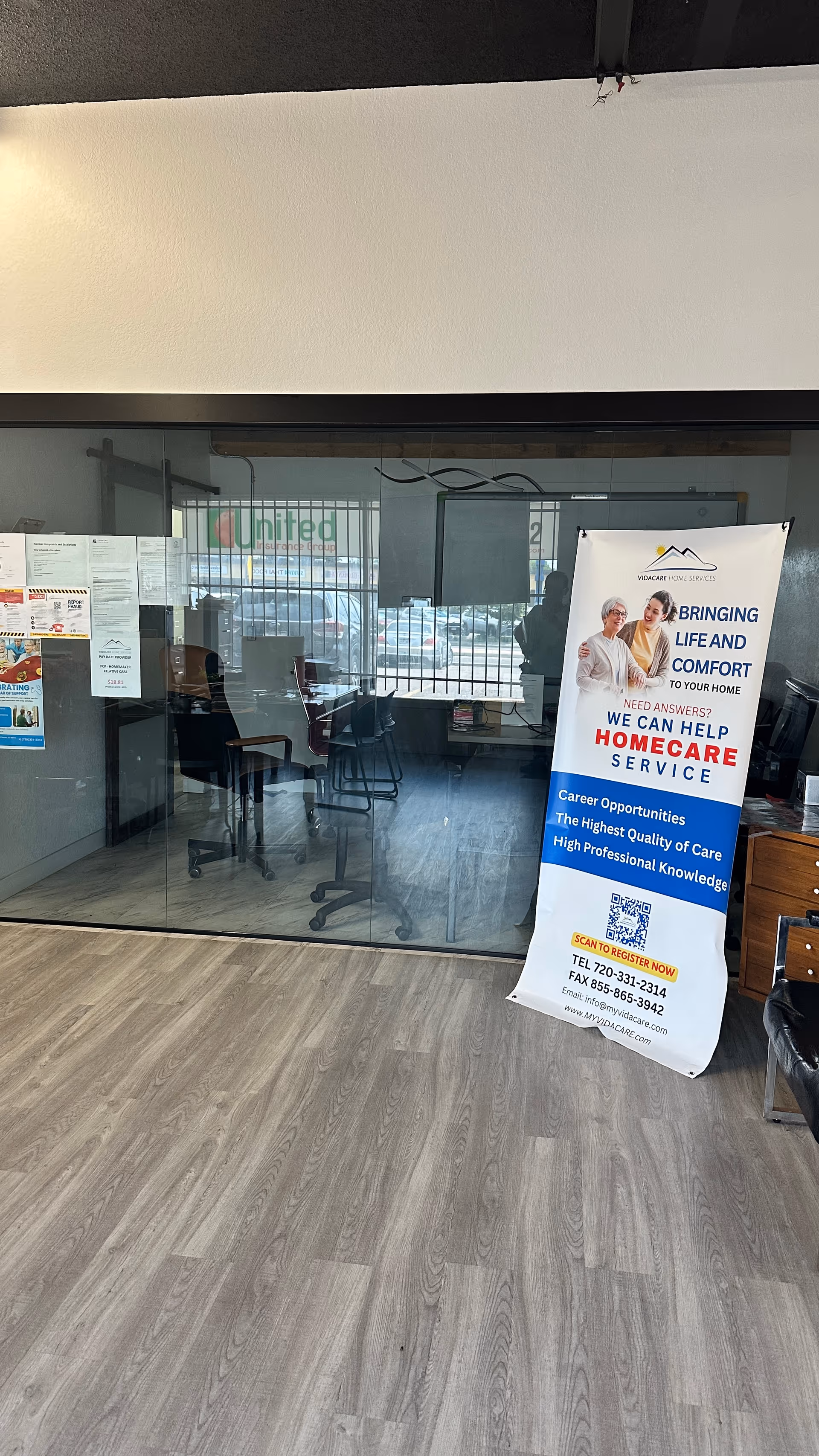 Glass-walled reception area with chairs and a standing VidaCare Home Services banner.