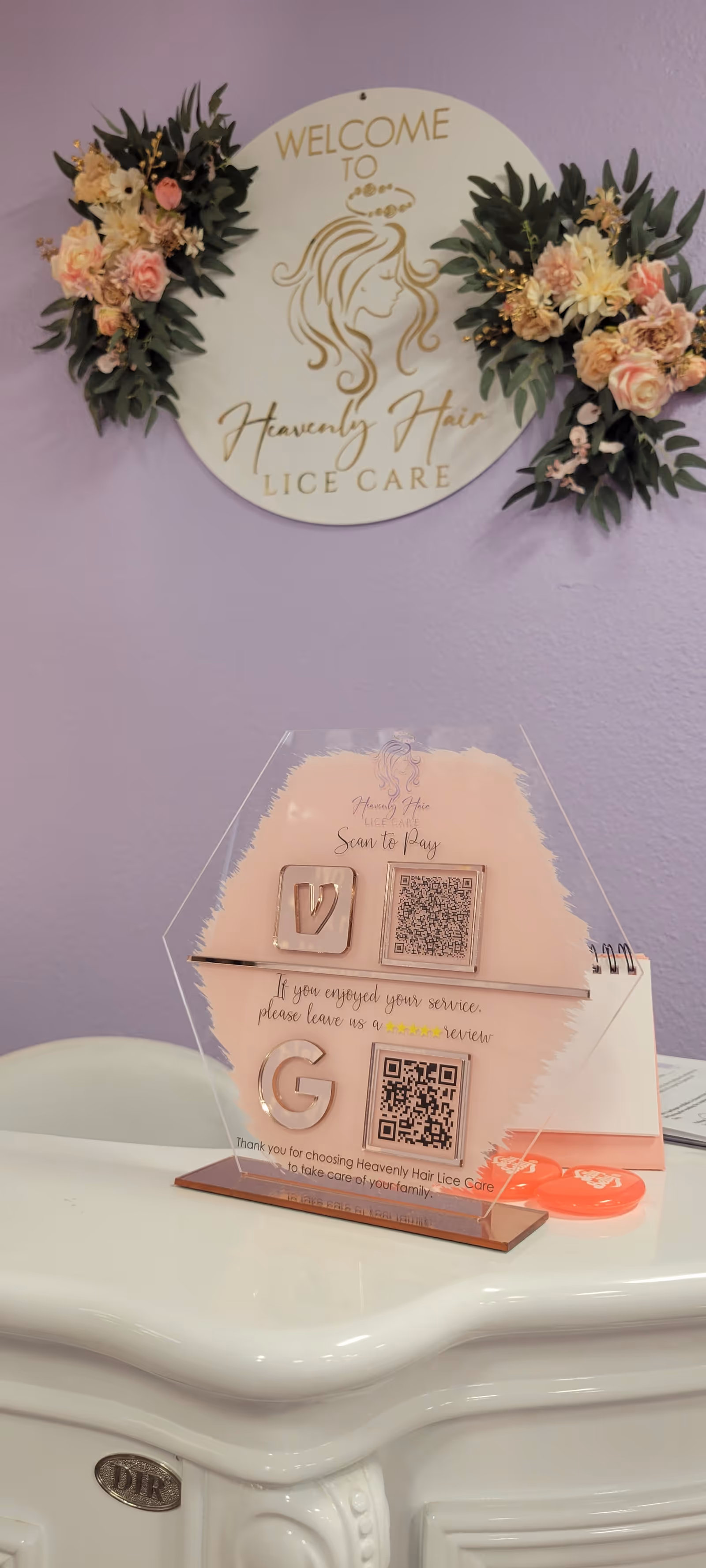Lavender-walled interior with a Welcome to Heavenly Hair Lice Care sign and floral accents.