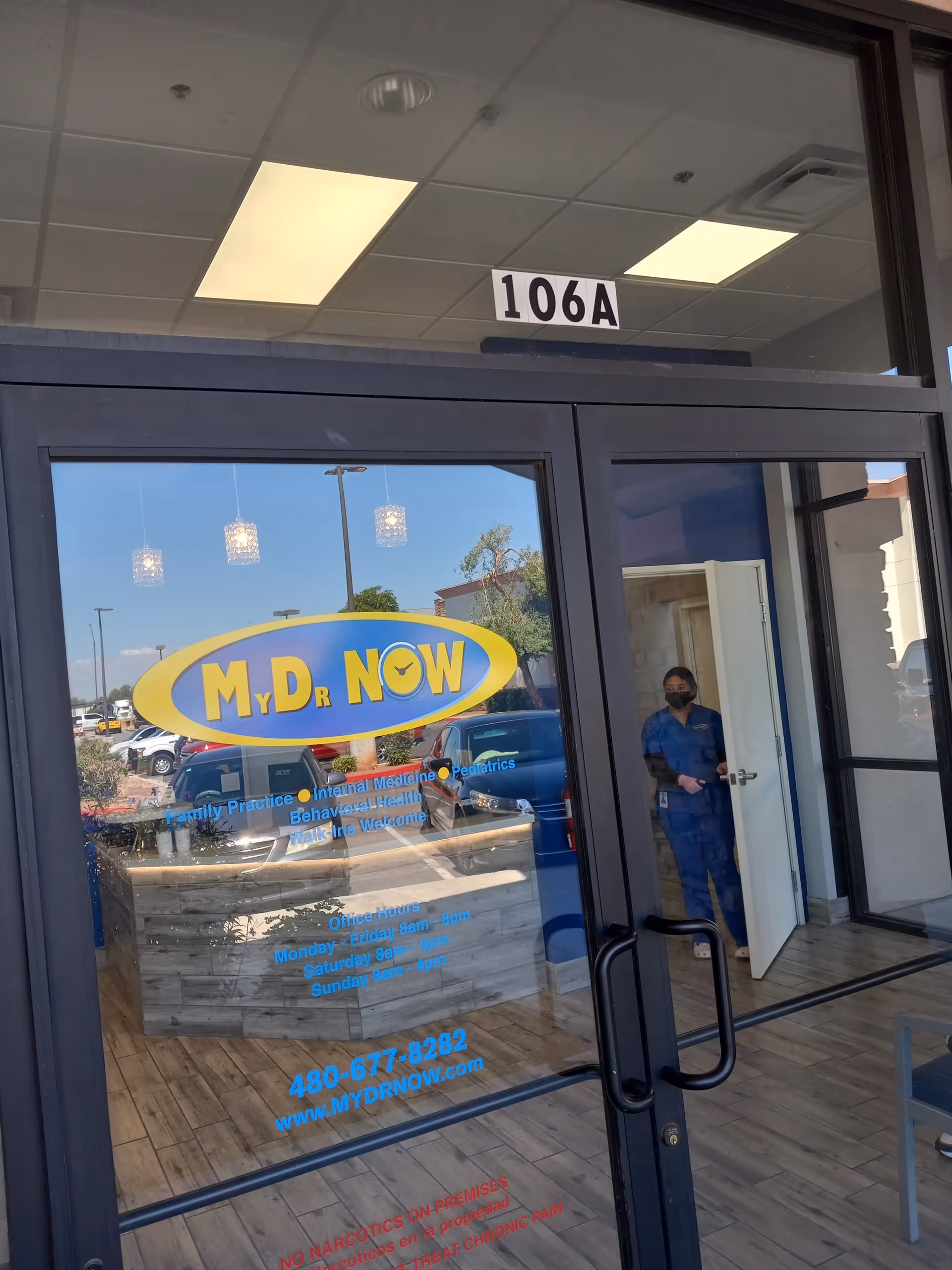 Glass entrance of MY DR NOW with 106A sign, person in scrubs at doorway.