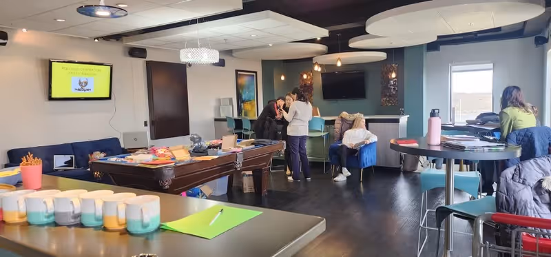 Activity-filled senior living lounge with couches, tables, and residents socializing indoors.