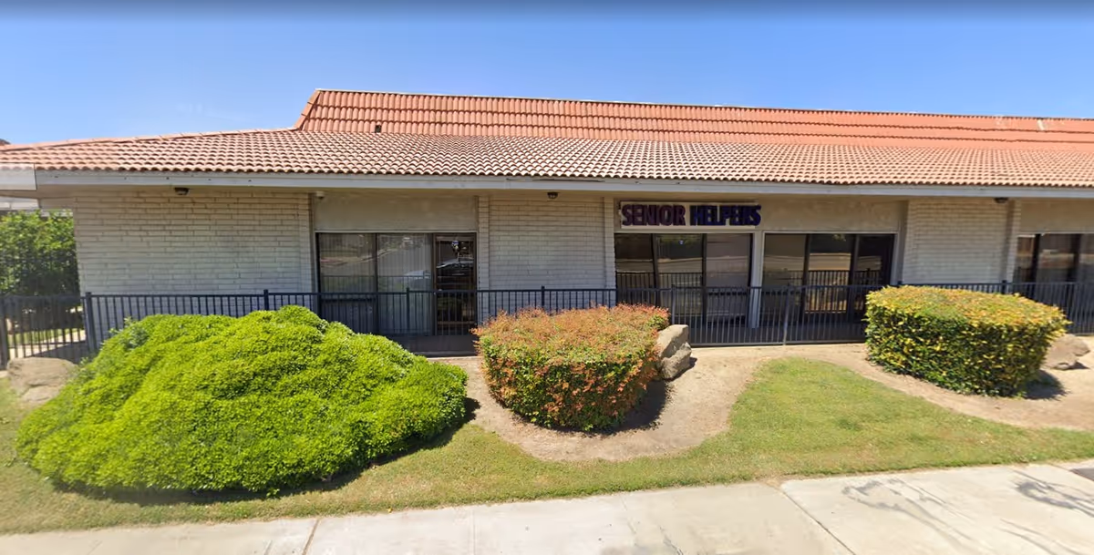 Single-story building with a red-tiled roof and front landscaping, Senior Helpers sign.