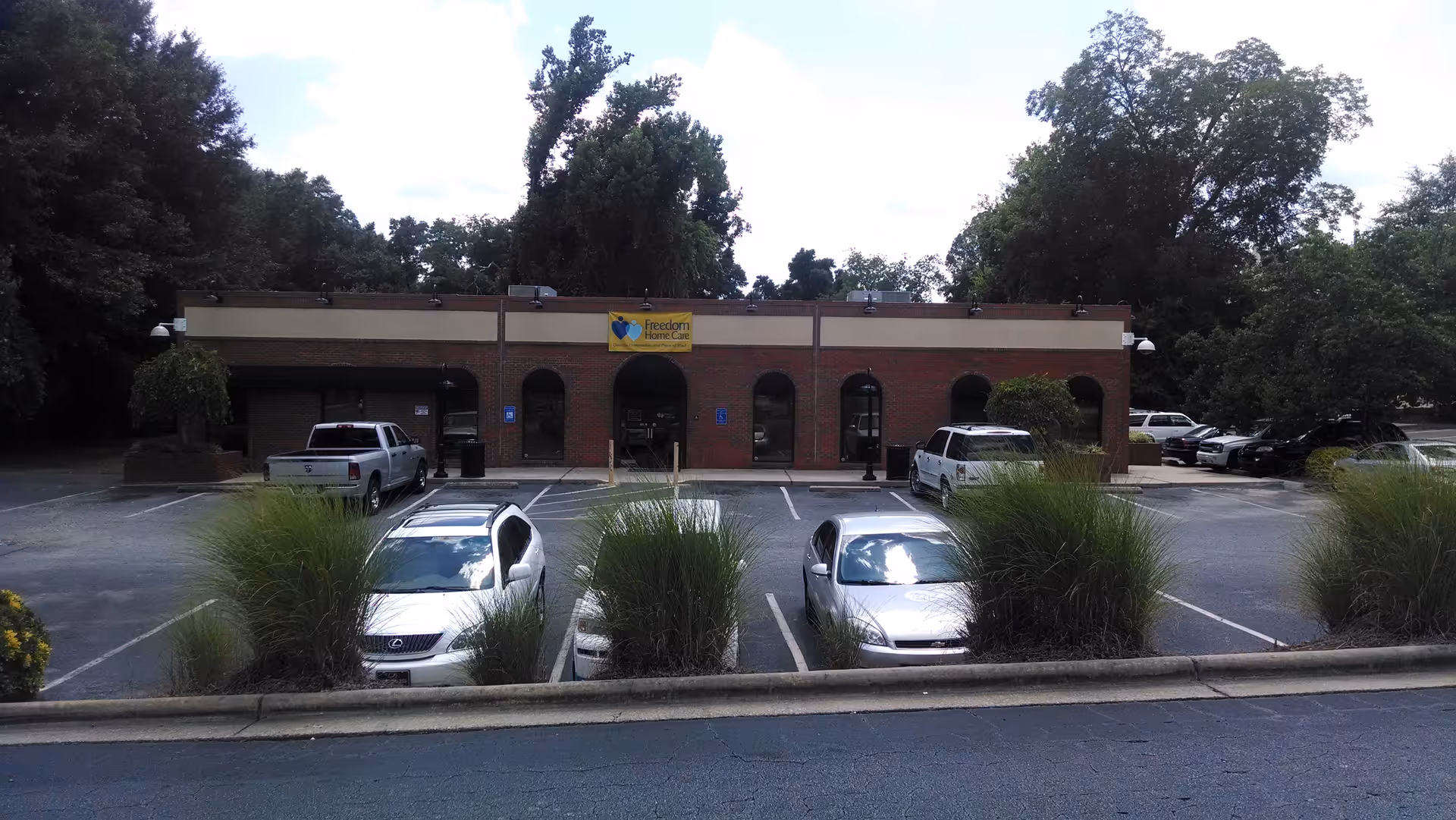 Brick senior living facility front with parked cars and a Freedom Adult Care sign.
