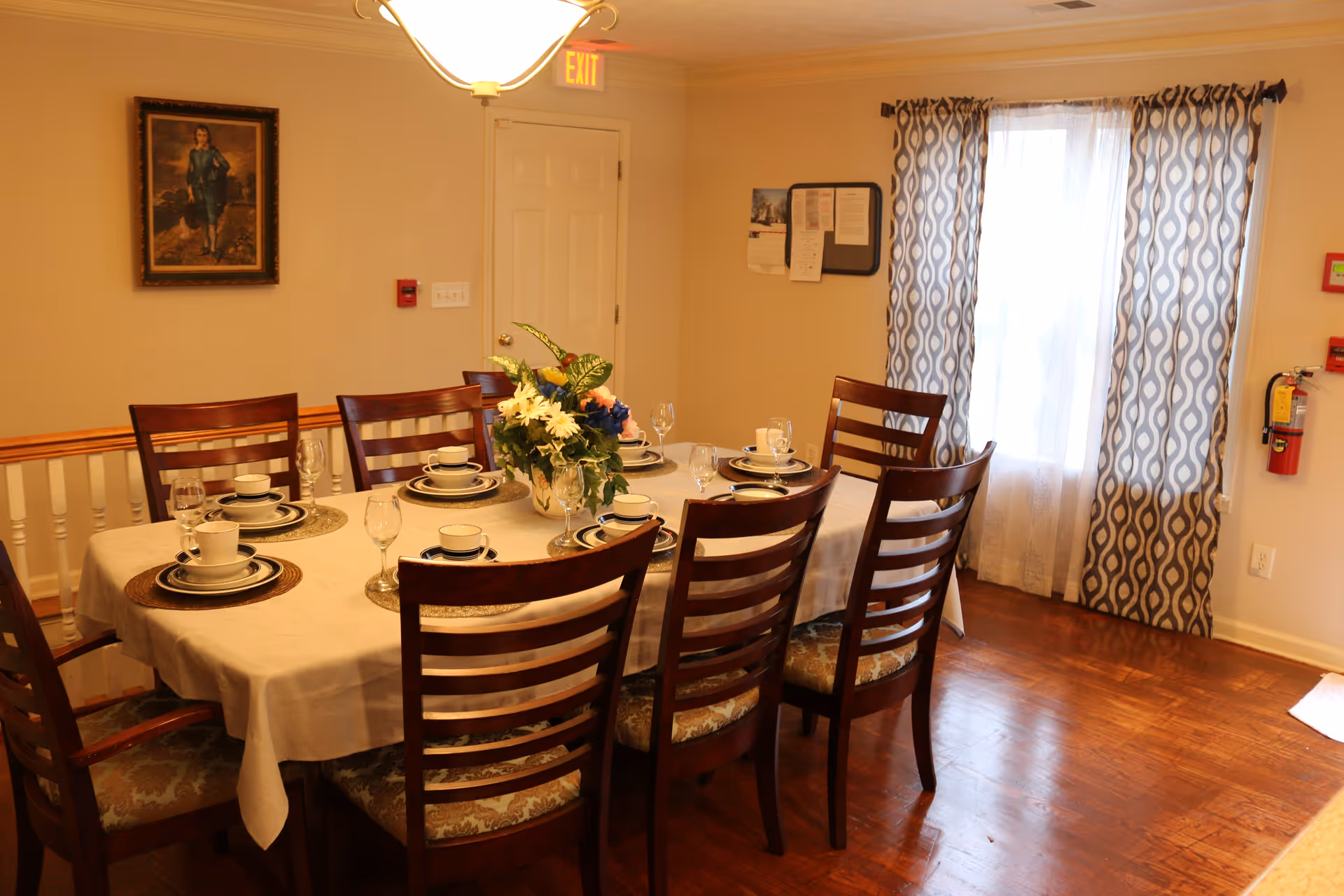 A dining room with a table set for eight in a senior living facility.
