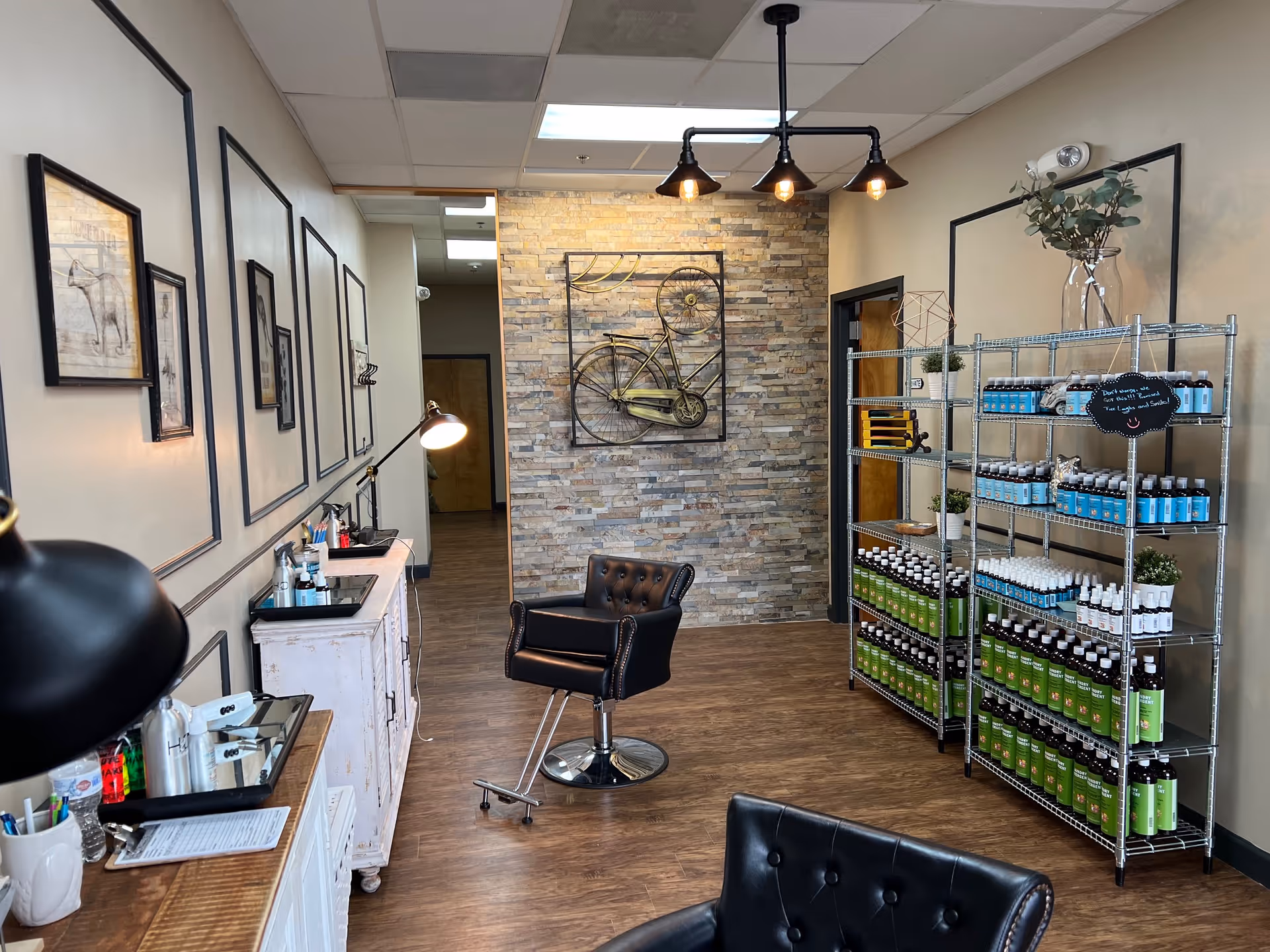 Hair salon interior with a styling chair, sinks, and product shelving.