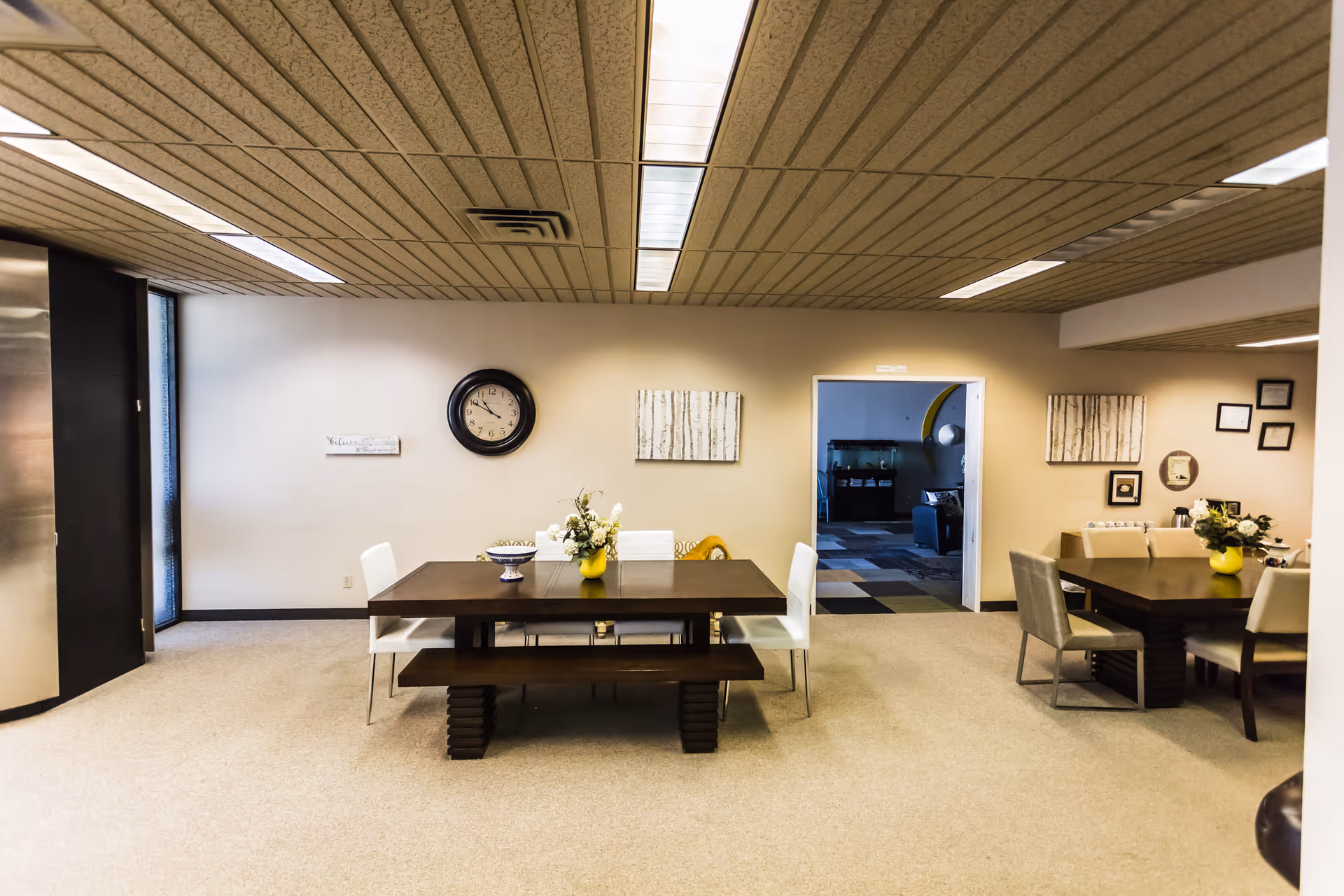 Interior dining area with two tables, chairs, benches, and wall decor.