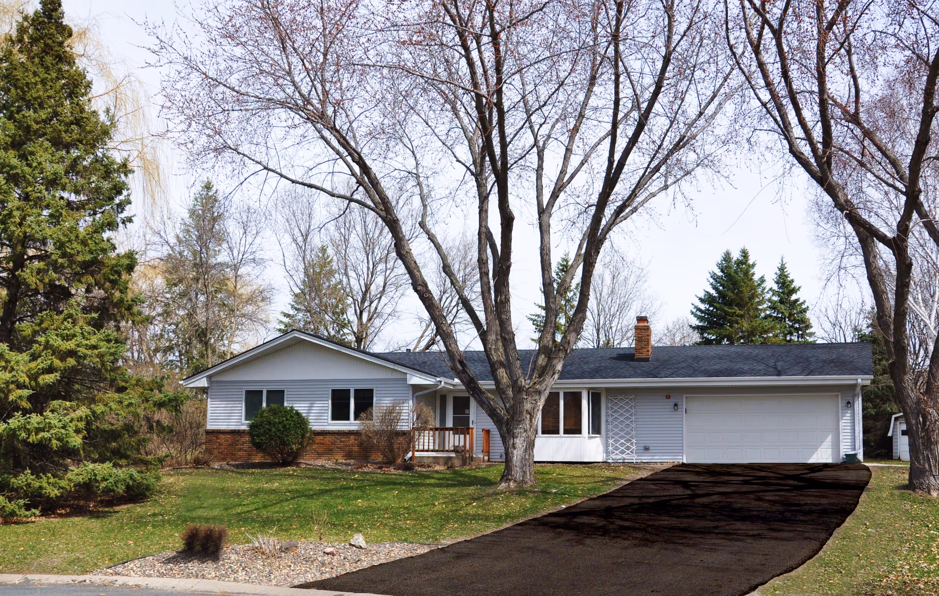 Front view of a single-story facility with a driveway, trees, and a two-car garage.