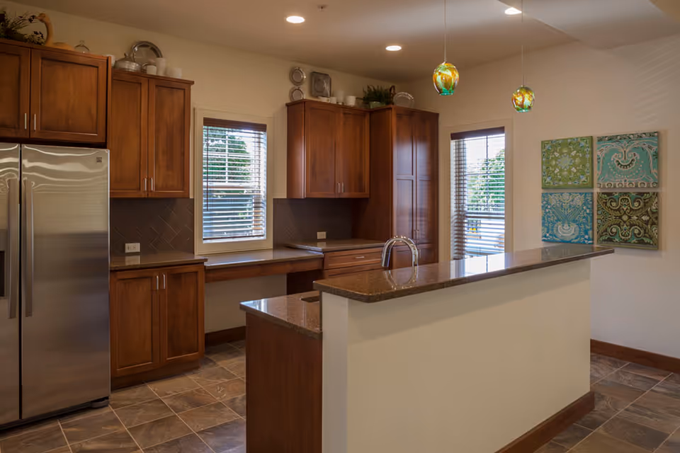 Modern kitchen with wooden cabinets, island, pendant lights, and stainless steel appliances.