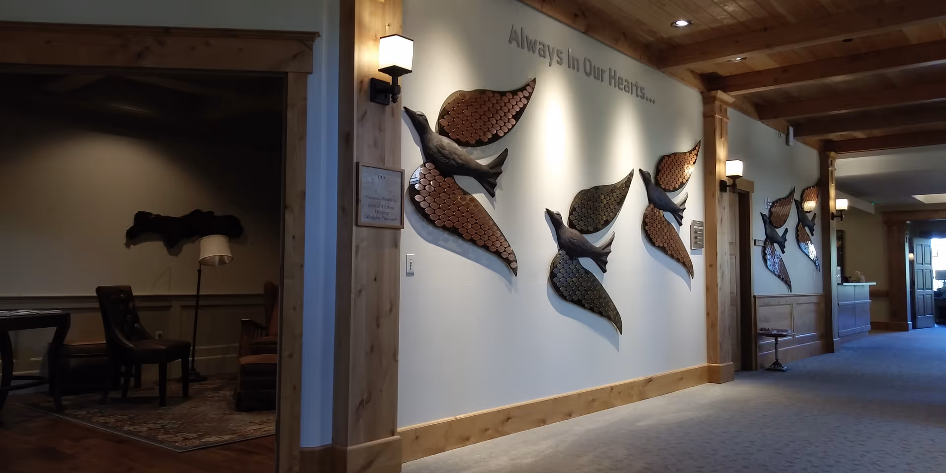 Interior hallway with wooden beams, wall fish sculptures, and a left-side seating area.