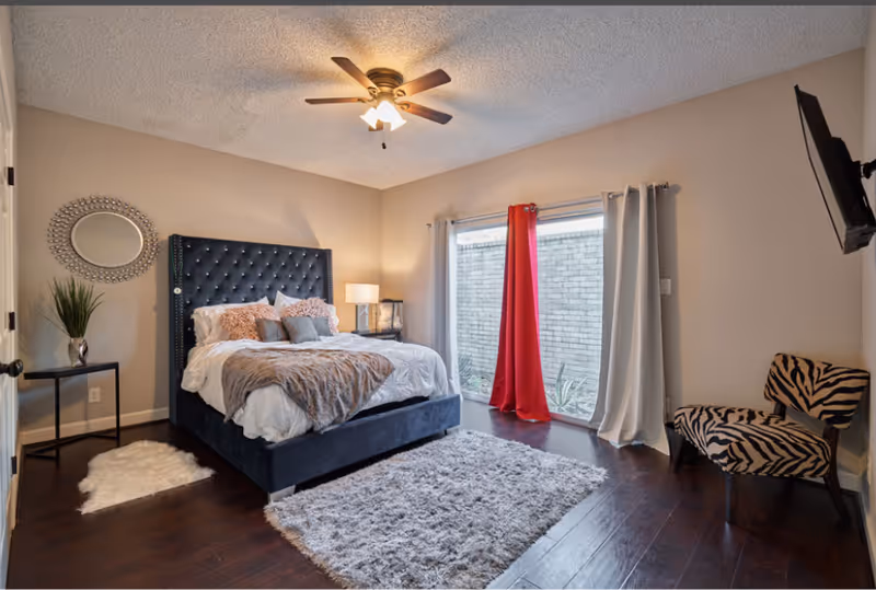 A modern bedroom with a plush bed, nightstands, rug, and zebra-pattern chair.