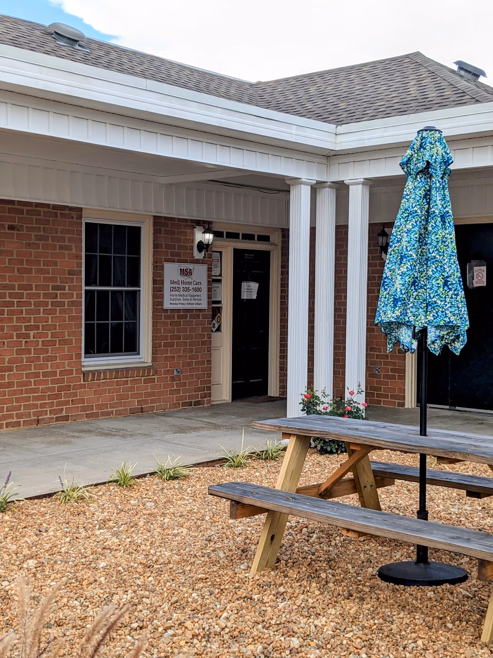 Exterior view of Medi Home Care facility with brick walls, patio table, and umbrella.