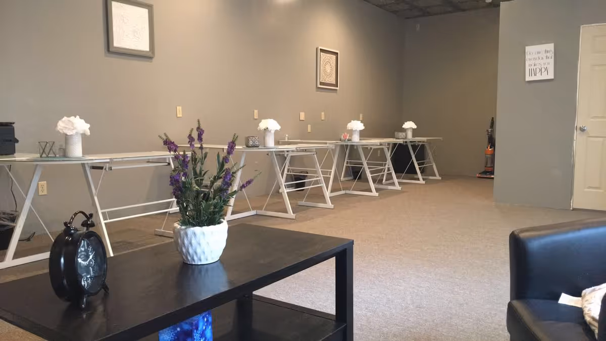 Long multipurpose room with folding tables along back wall and a black coffee table in foreground.