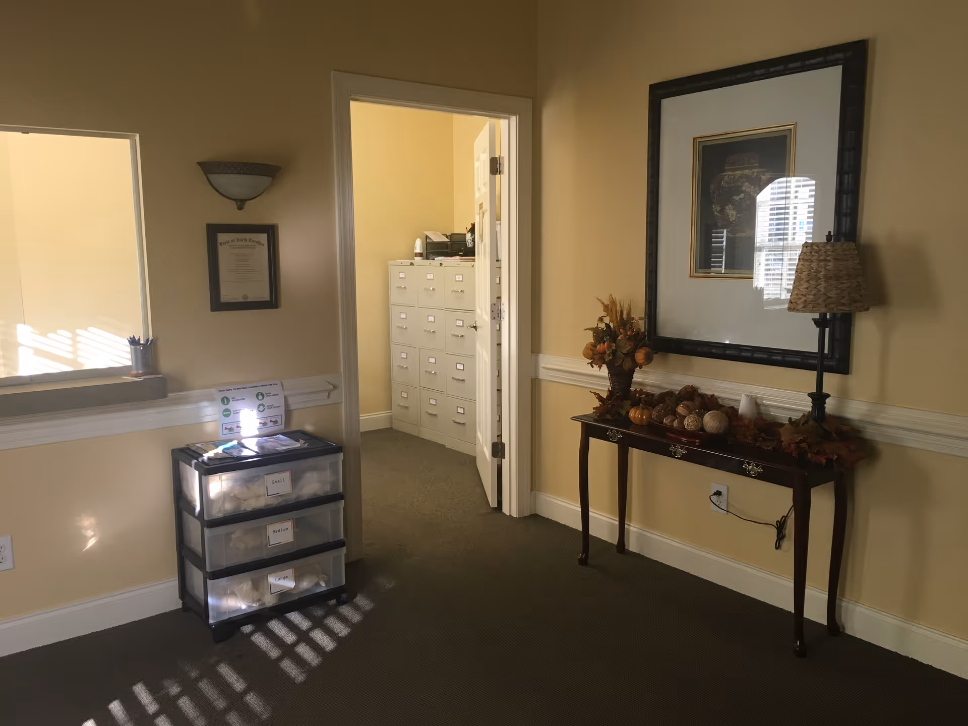 Hallway interior of a senior living facility featuring a storage cart and decorative console table.