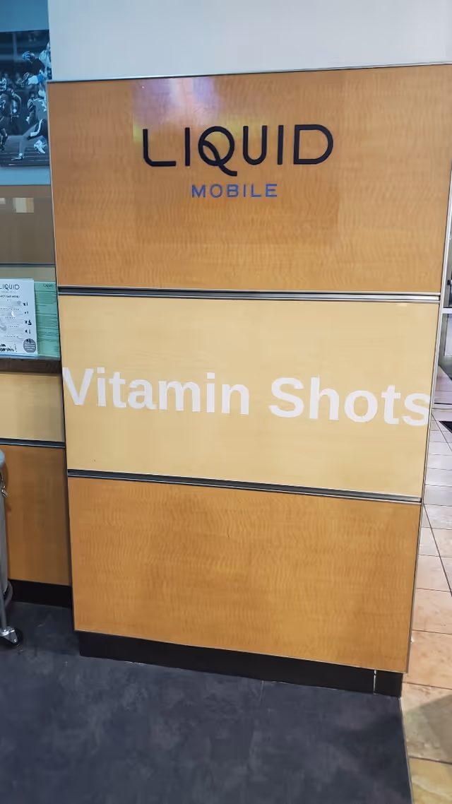 Wood-paneled reception counter with Liquid Mobile sign and Vitamin Shots lettering