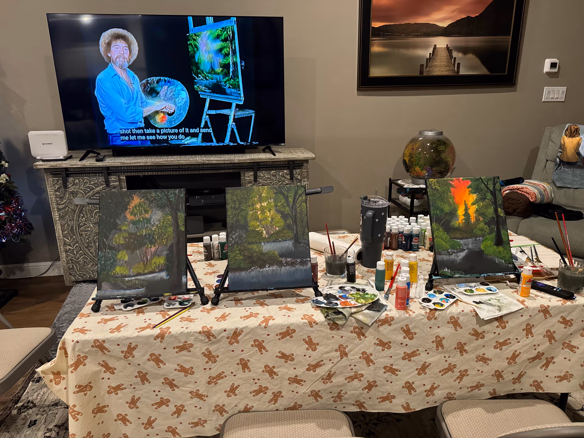 Indoor living room with art table, canvases, paints, and a TV.