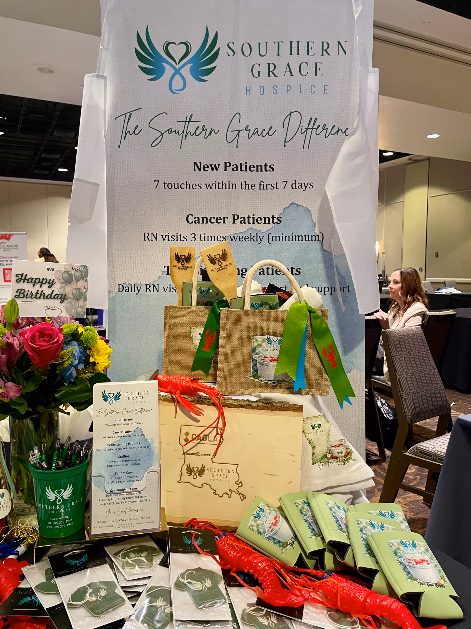 A large indoor hospice booth displays a Southern Grace banner with flowers, bags, and brochures.