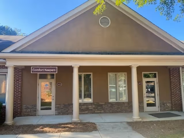 Front exterior of a Comfort Keepers facility with columns and entrance doors.
