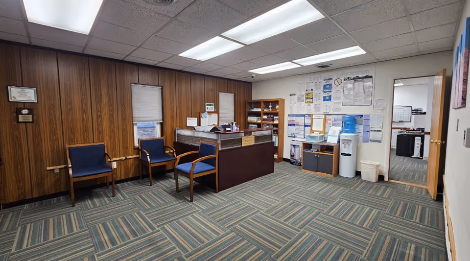 An interior reception area with wood-paneled walls, seating, and a front desk.