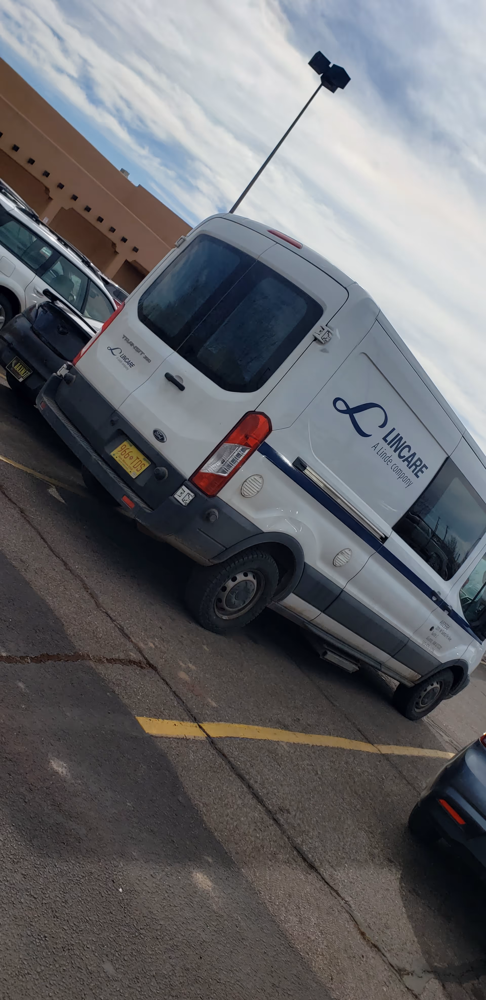 White LINCARE van parked outside a senior living facility with tan exterior.