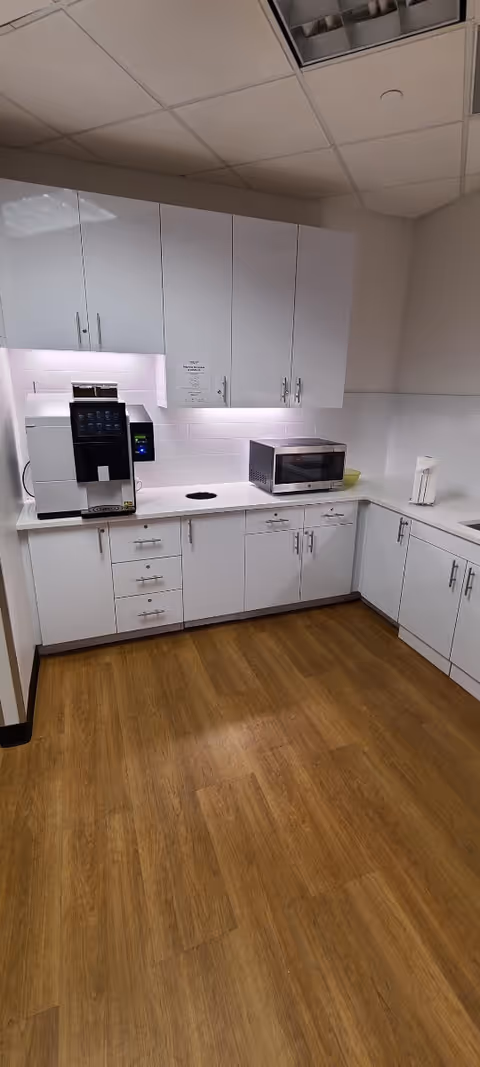White kitchen with cabinets, microwave, coffee maker, and wood-look flooring.