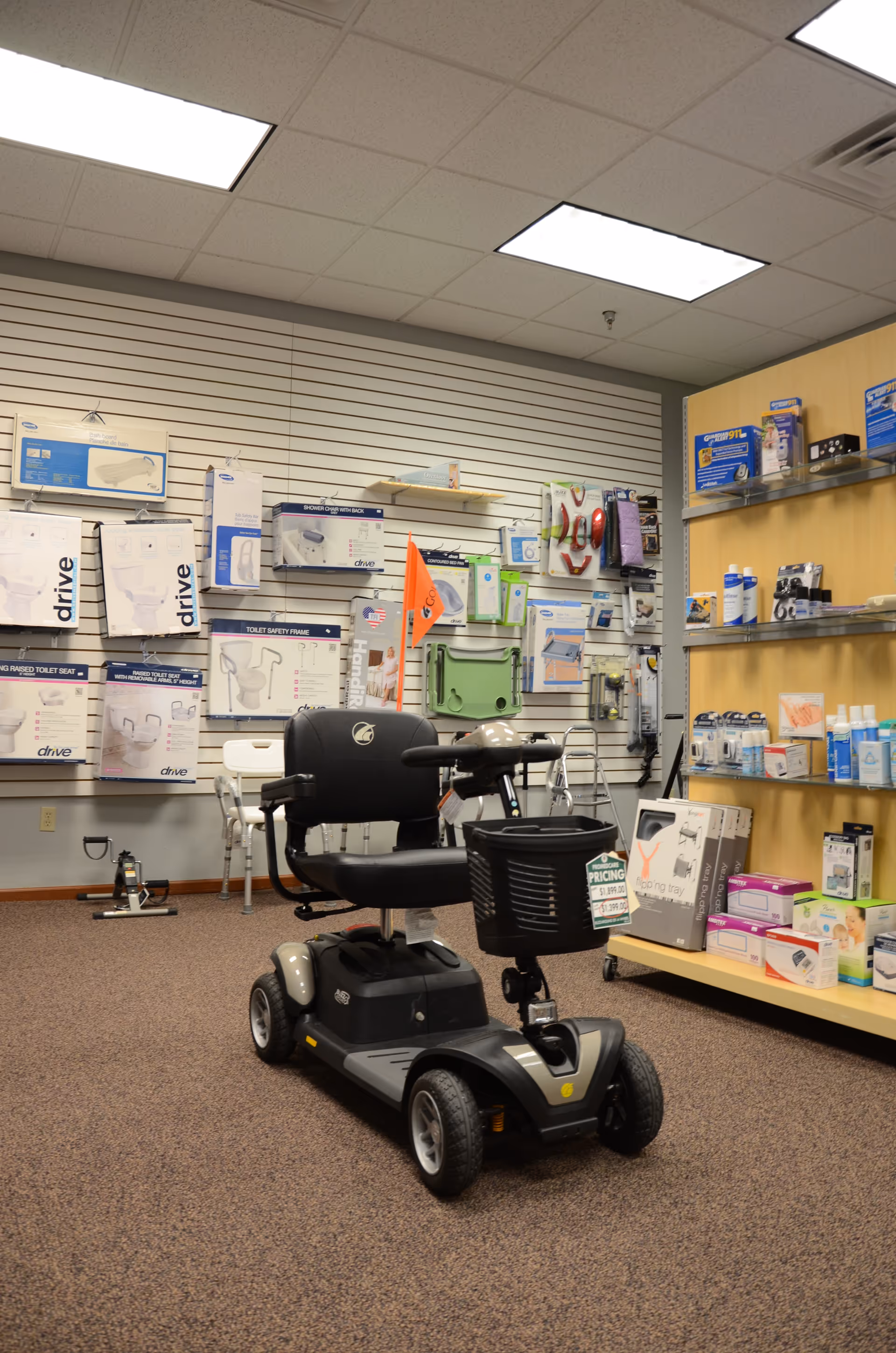 A mobility scooter sits on a showroom floor amid medical devices at Promedcare
