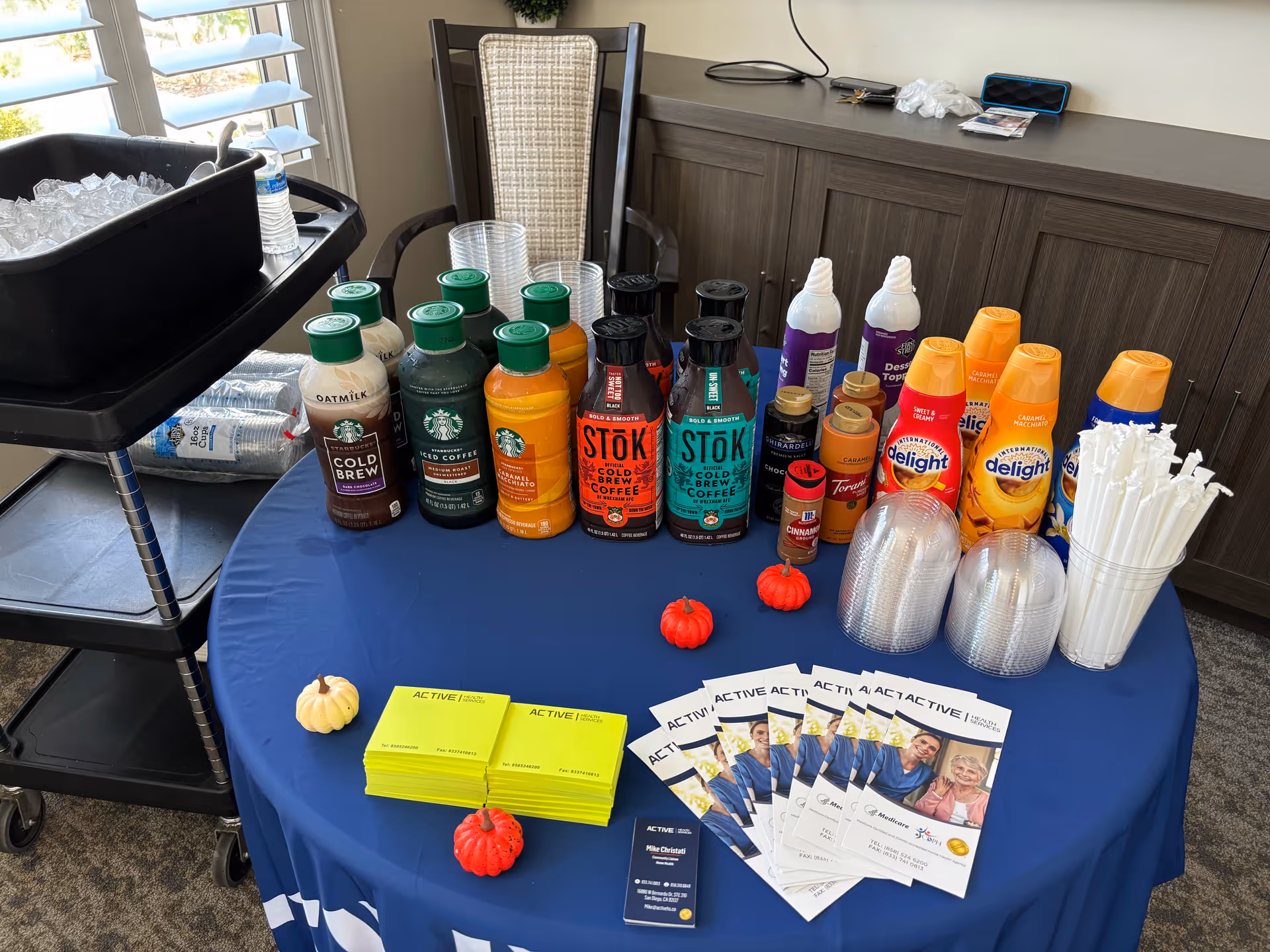 An indoor table displays beverage bottles, cups, and brochures for Active Health Services.