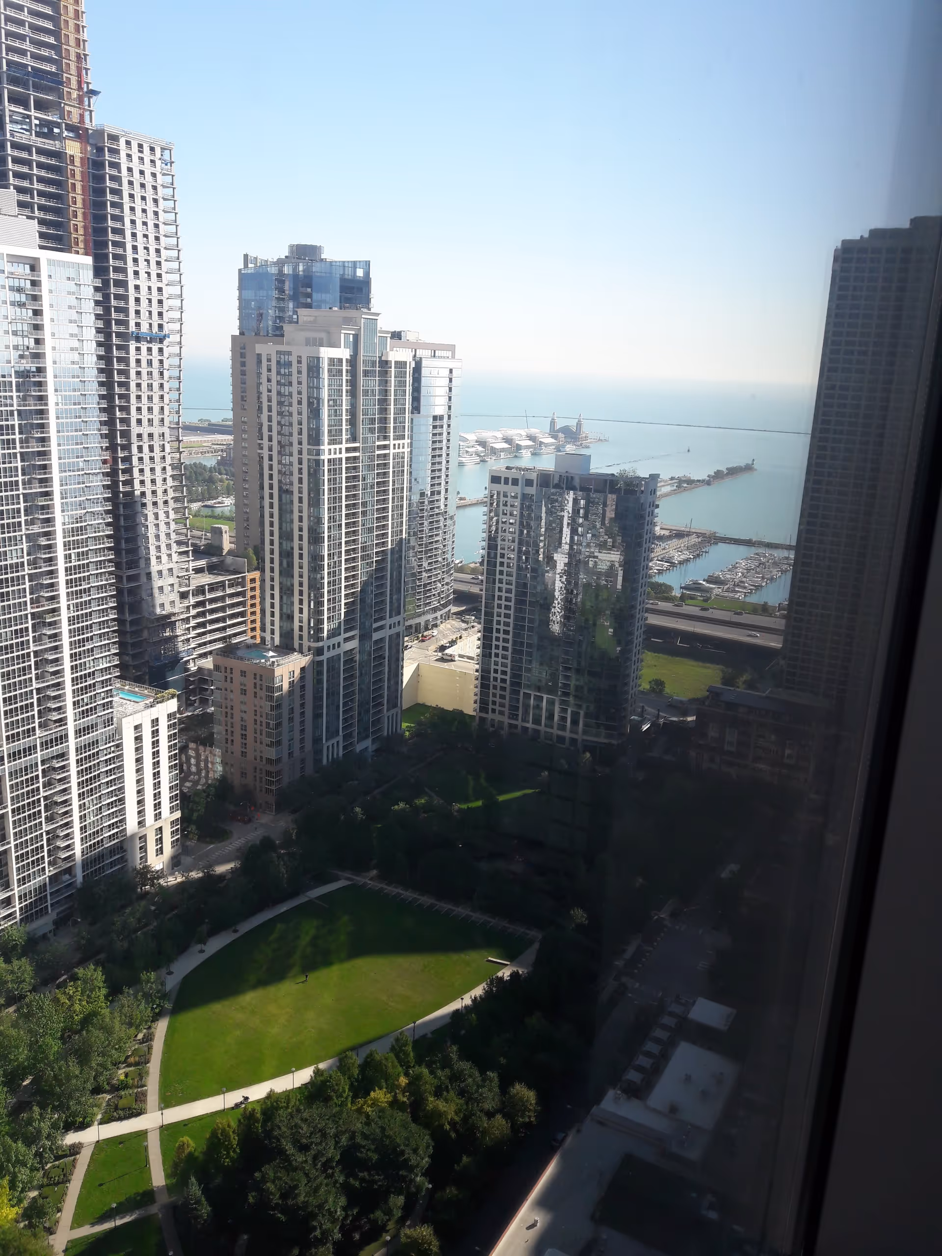 A high-rise cityscape with glass towers, a marina, and a green park below.