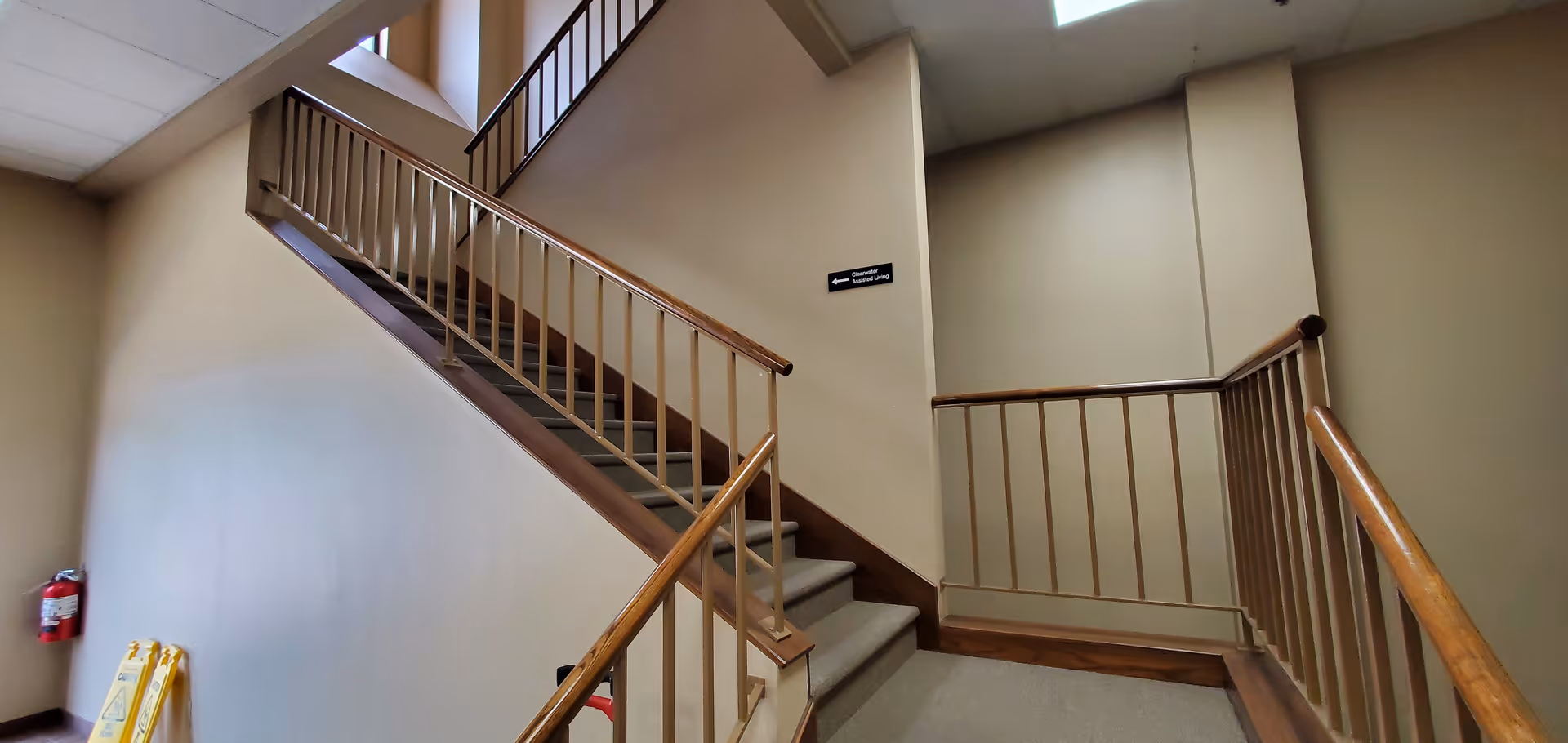 Indoor stairwell with wooden handrails and beige walls.