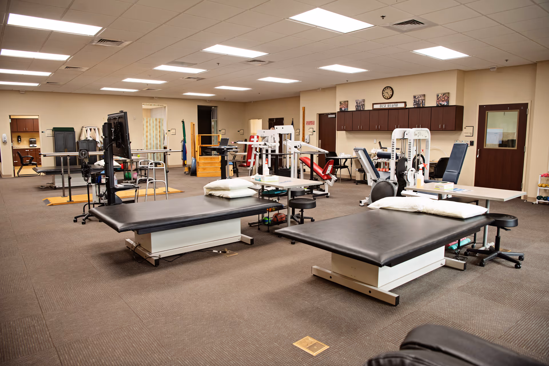 Rehabilitation gym inside a senior facility with therapy tables and exercise equipment.