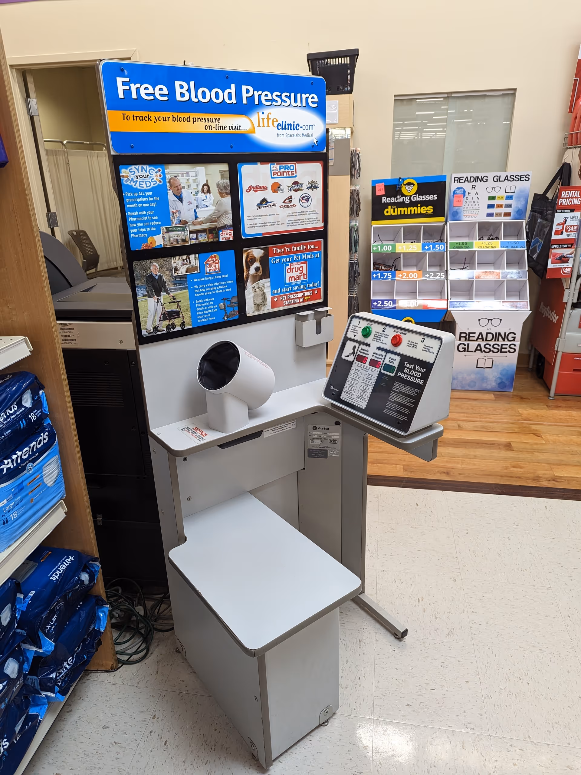 Blood pressure monitor kiosk with instructional panel inside Discount Drug Mart pharmacy.