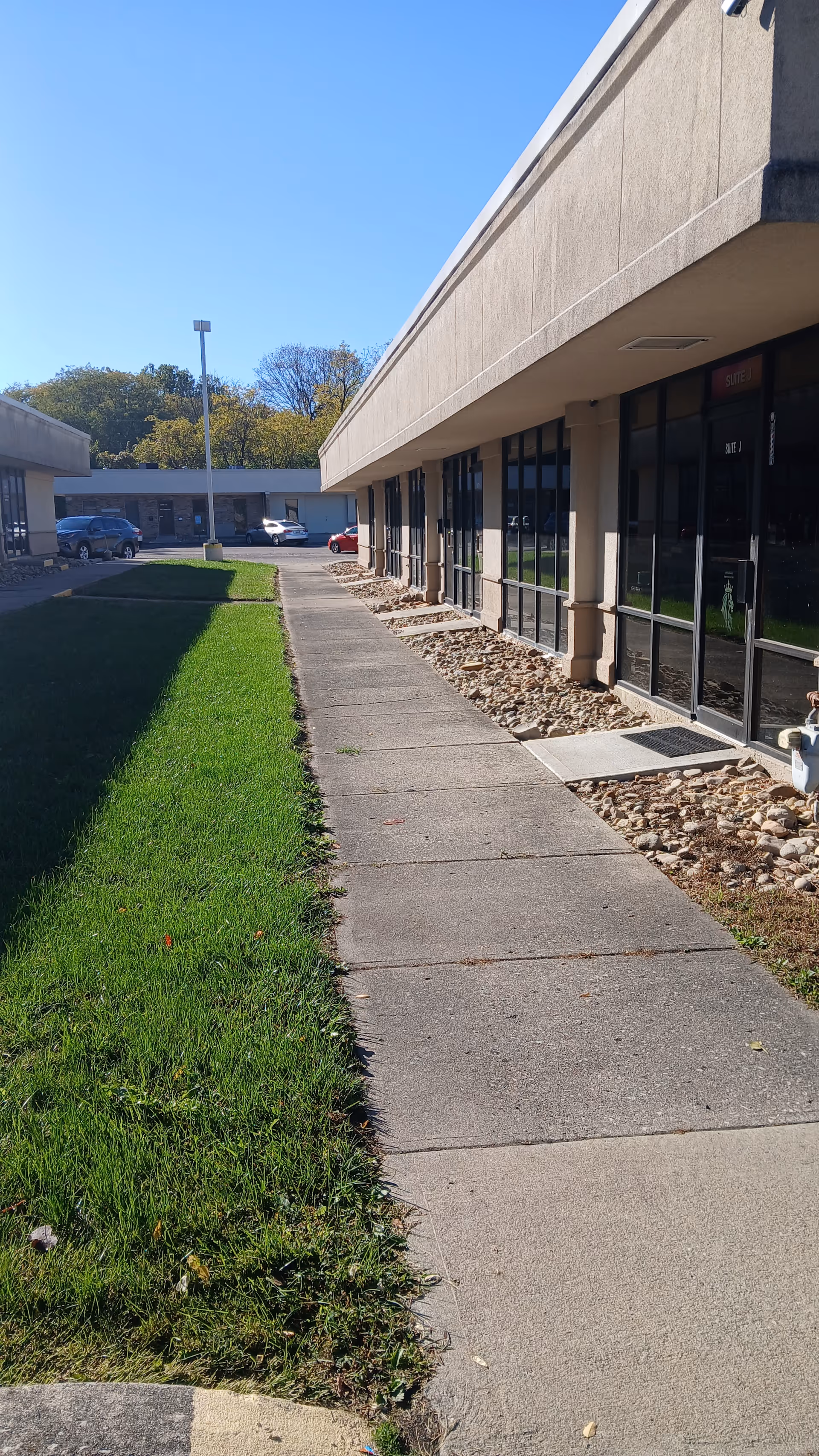 Exterior view of a senior living facility with sidewalk, glass doors, and landscaping.