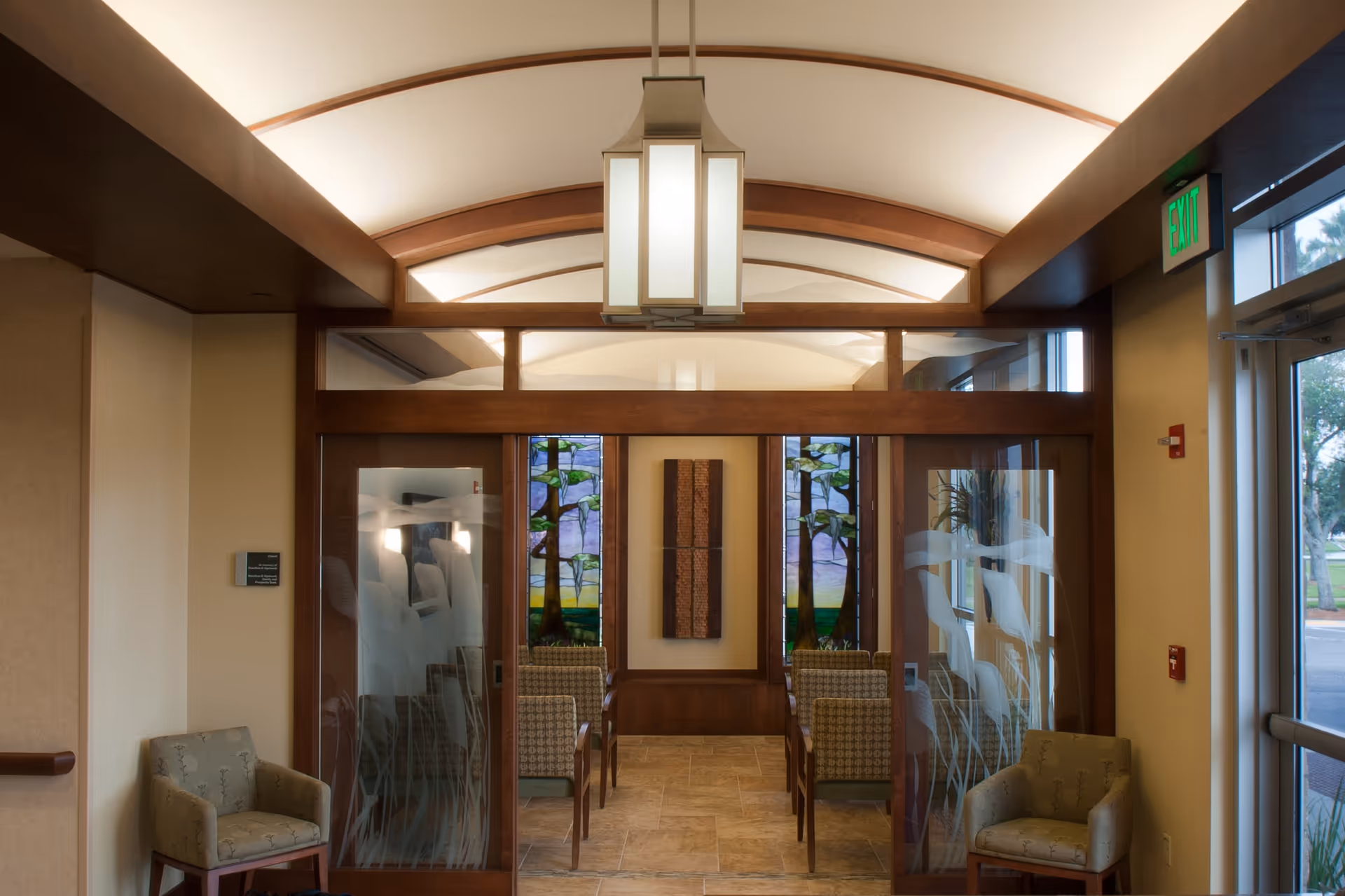 Interior view of a welcoming lobby with glass doors, stained panels, and seating.