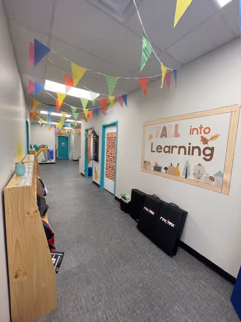 Colorful hallway with bunting, learning wall art, and storage shelves along the corridor