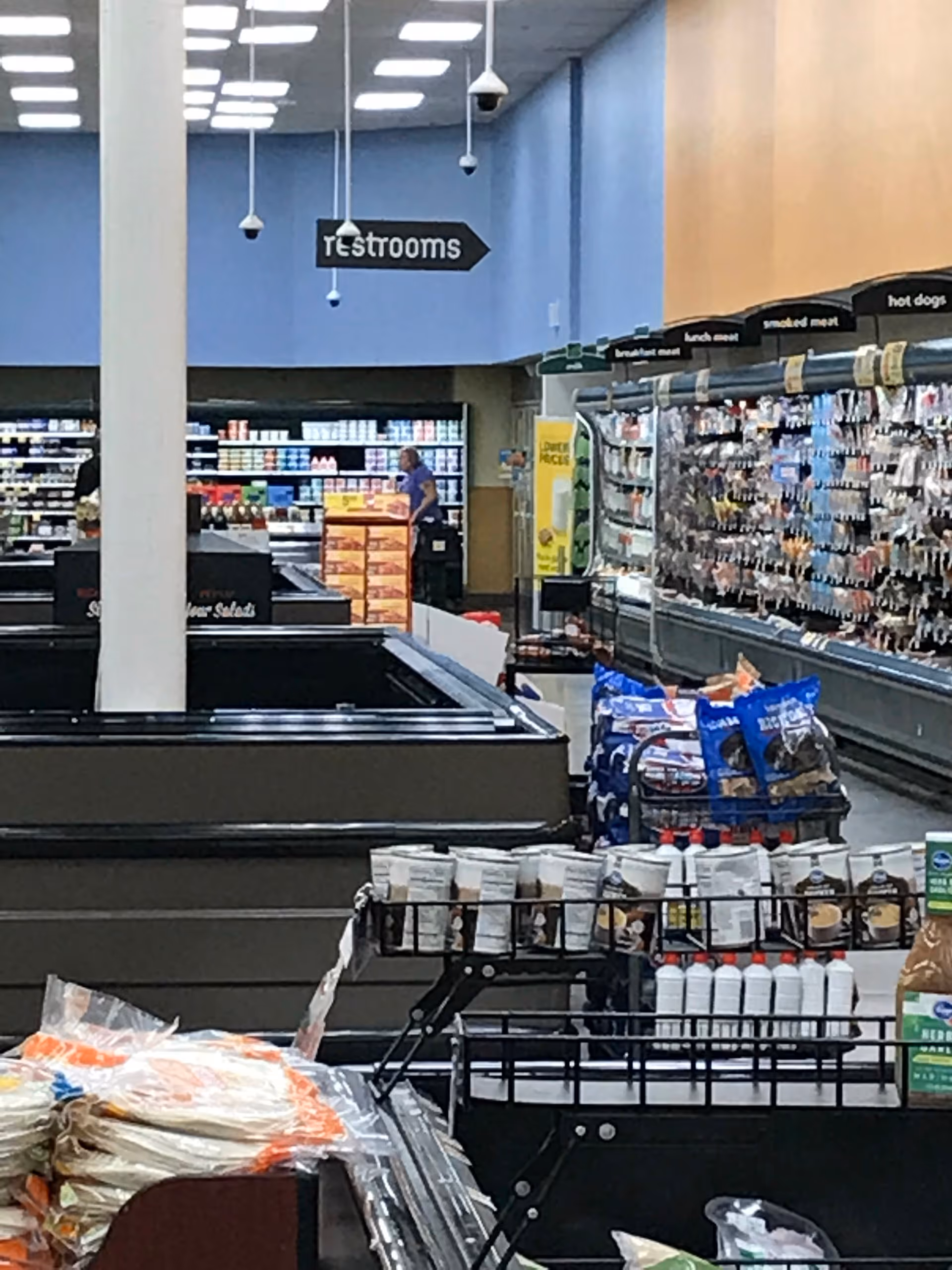 Inside a Kroger store, aisles and products with a restroom sign overhead.