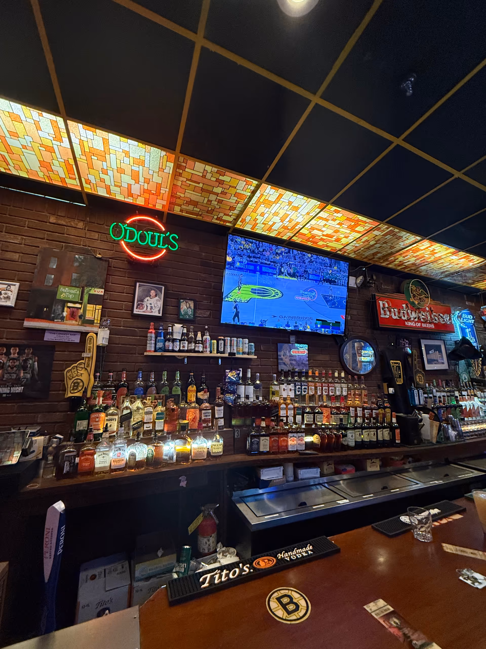 Bar area inside a senior facility with liquor bottles, neon sign, and TV