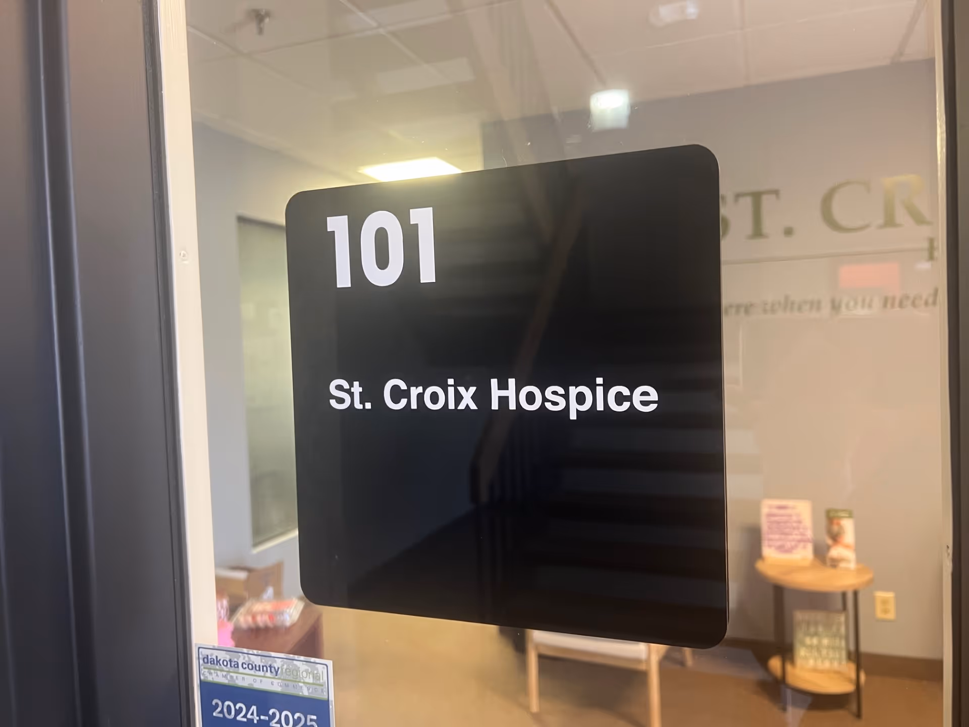Glass door with 101 St. Croix Hospice sign and a small round table inside.