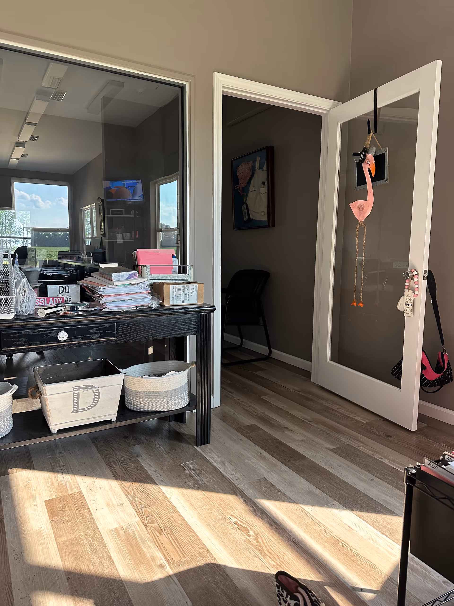 Interior office area with a dark desk, papers, and a doorway with flamingo decoration.