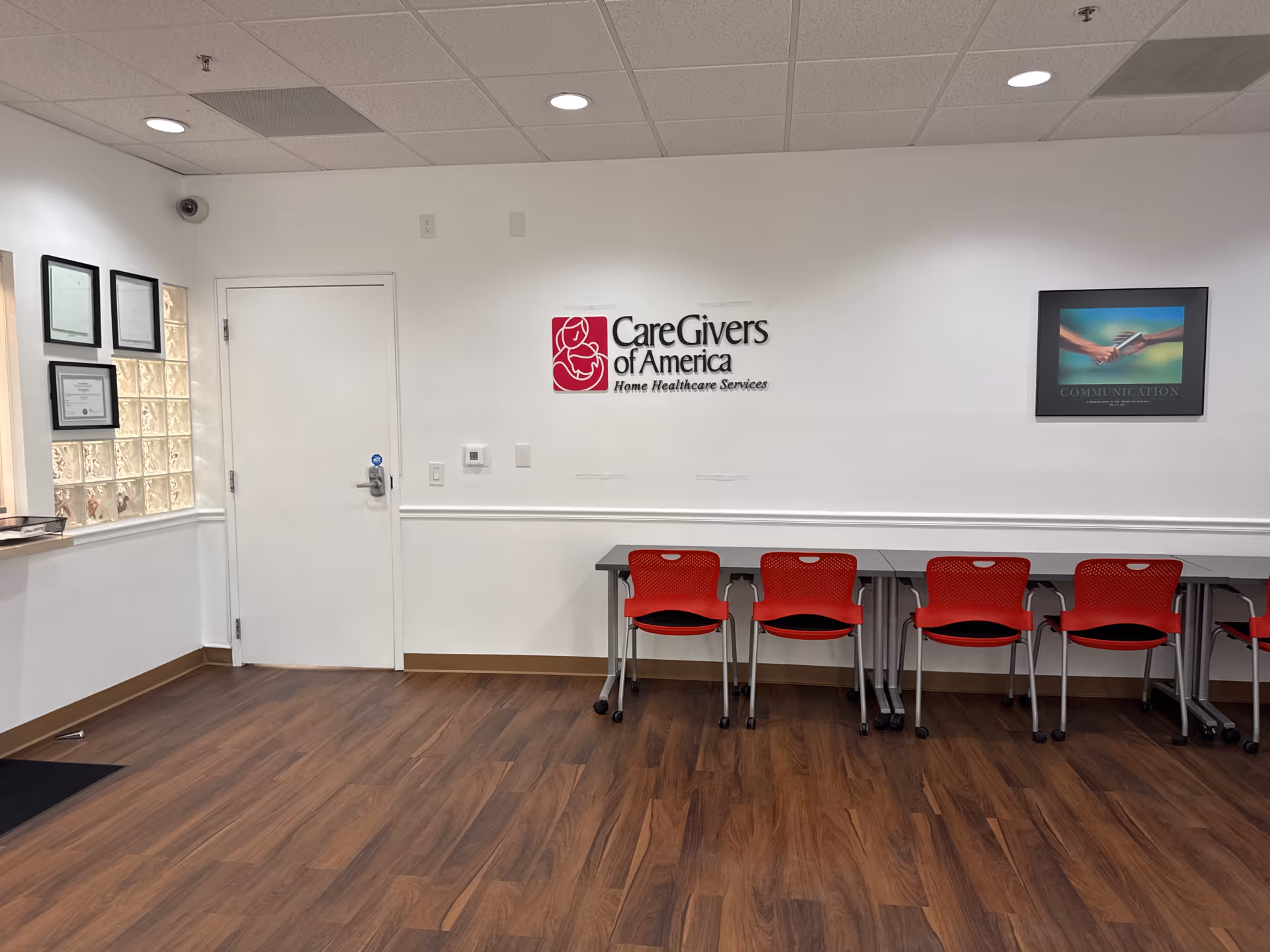 Reception area with red chairs and CareGivers of America logo on wall.