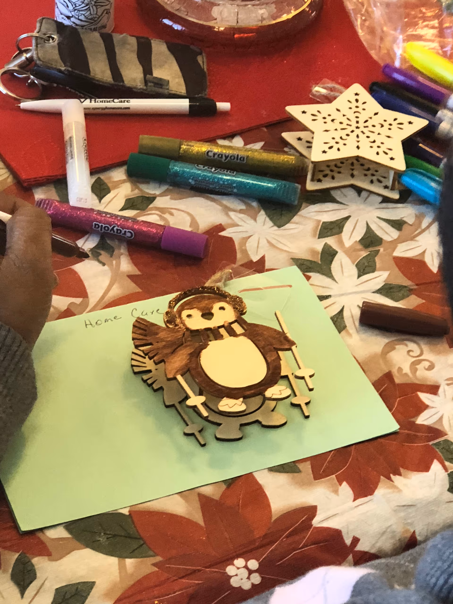 Craft table with markers, star ornament, and a turkey craft on a holiday tablecloth.