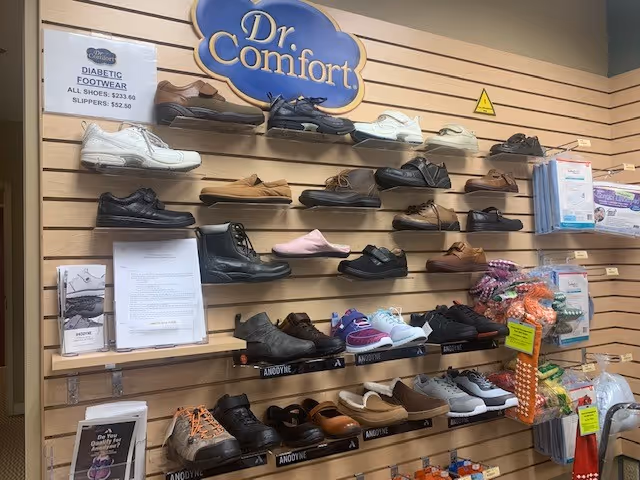 Wall display of orthopedic and diabetic shoes beneath a Dr. Comfort sign in interior corridor.