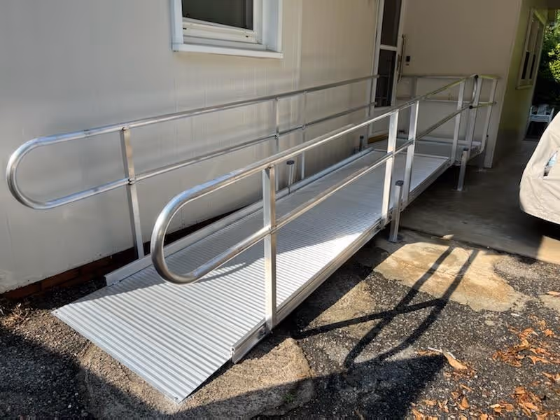 Exterior view of a metal wheelchair ramp along a building entrance.