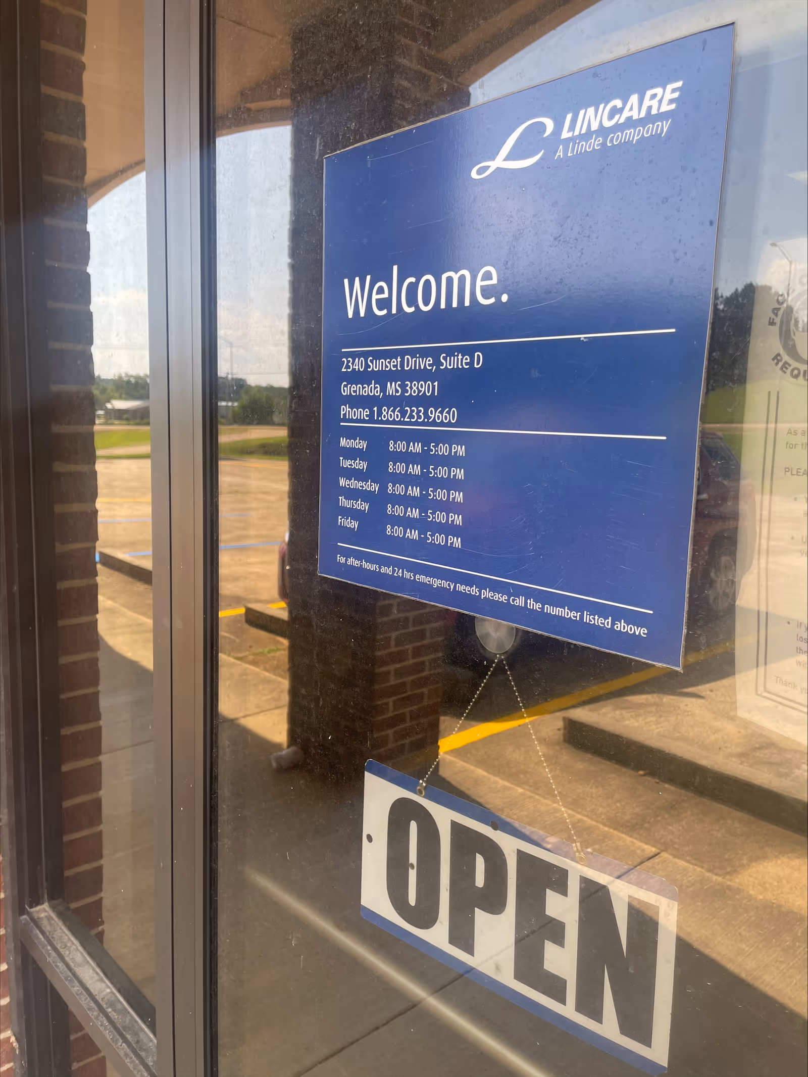 Lincare building entrance with blue Welcome sign and hanging OPEN sign on glass door.