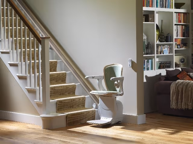 A stair lift chair mounted beside a carpeted staircase in a cozy living area.