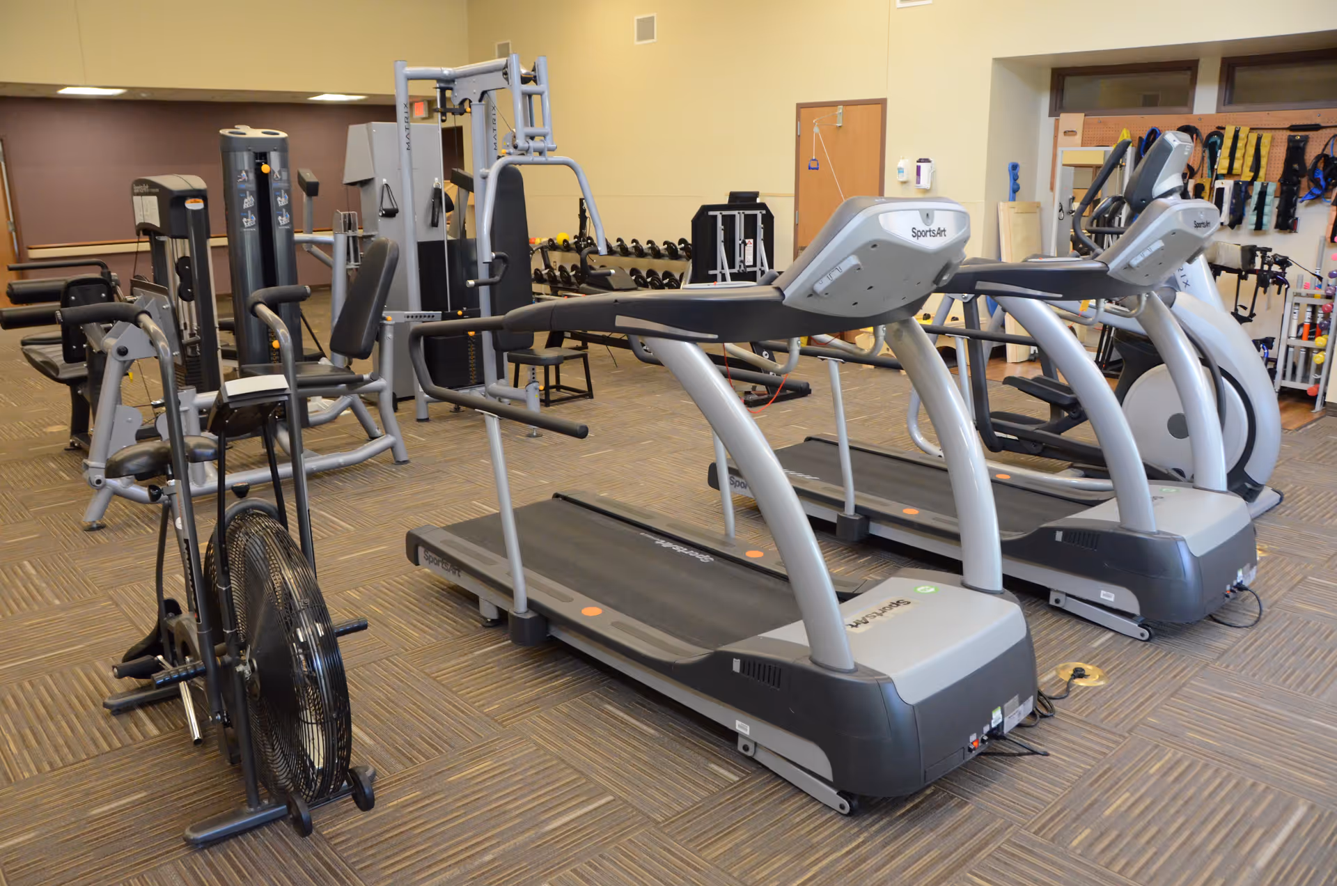 Indoor gym in a Regional Health Services of Howard County facility with treadmills, weight machines, equipment.