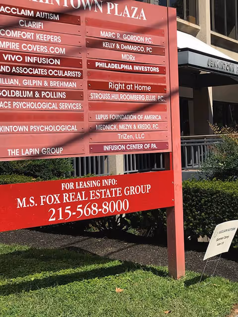 A large red signboard outside a building listing tenants, including Right at Home.